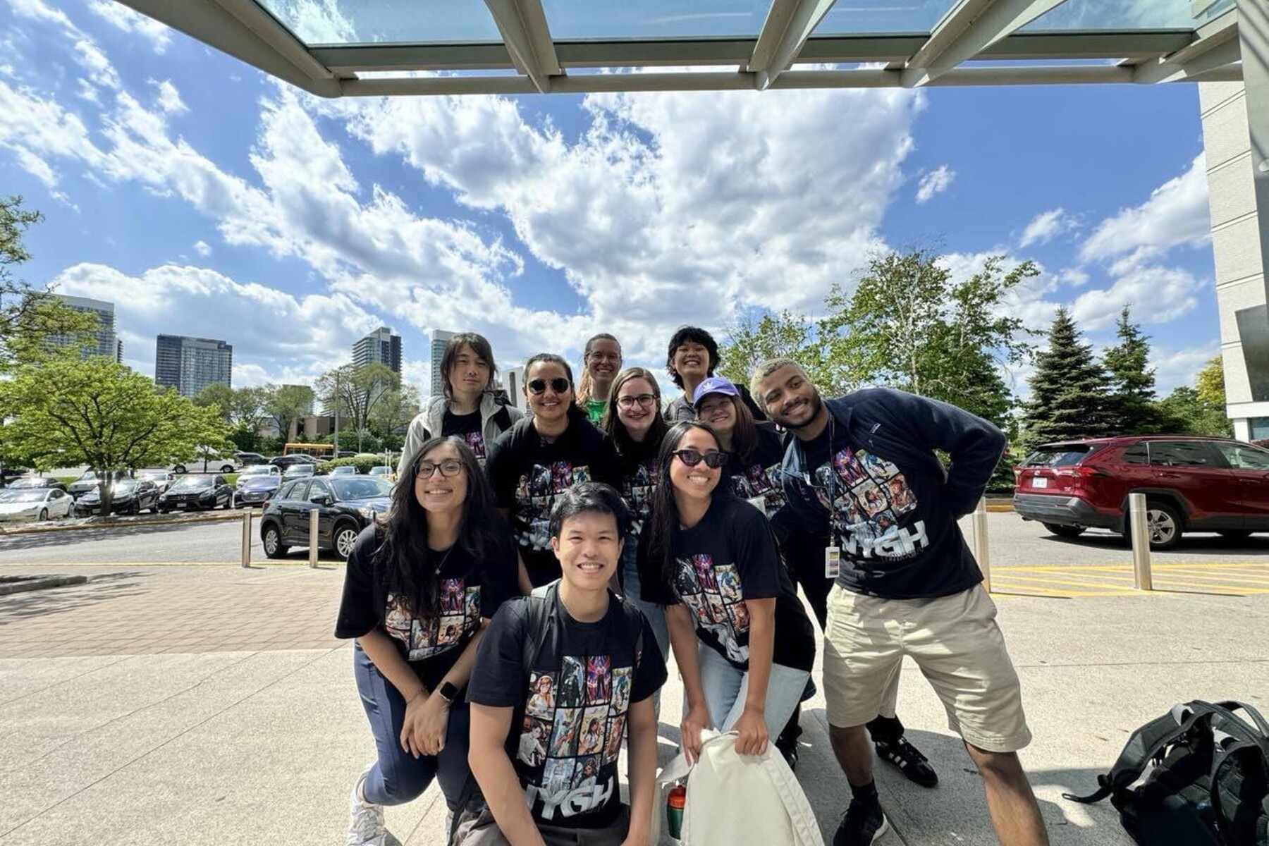 A group of people posing outside for a photo with sunny blue sky in the backdrop