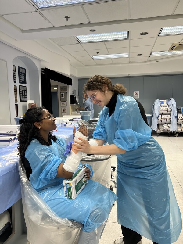 A person in blue gowns and blue gloves holding a cast