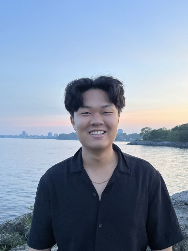 A person smiling at the camera with beach in background